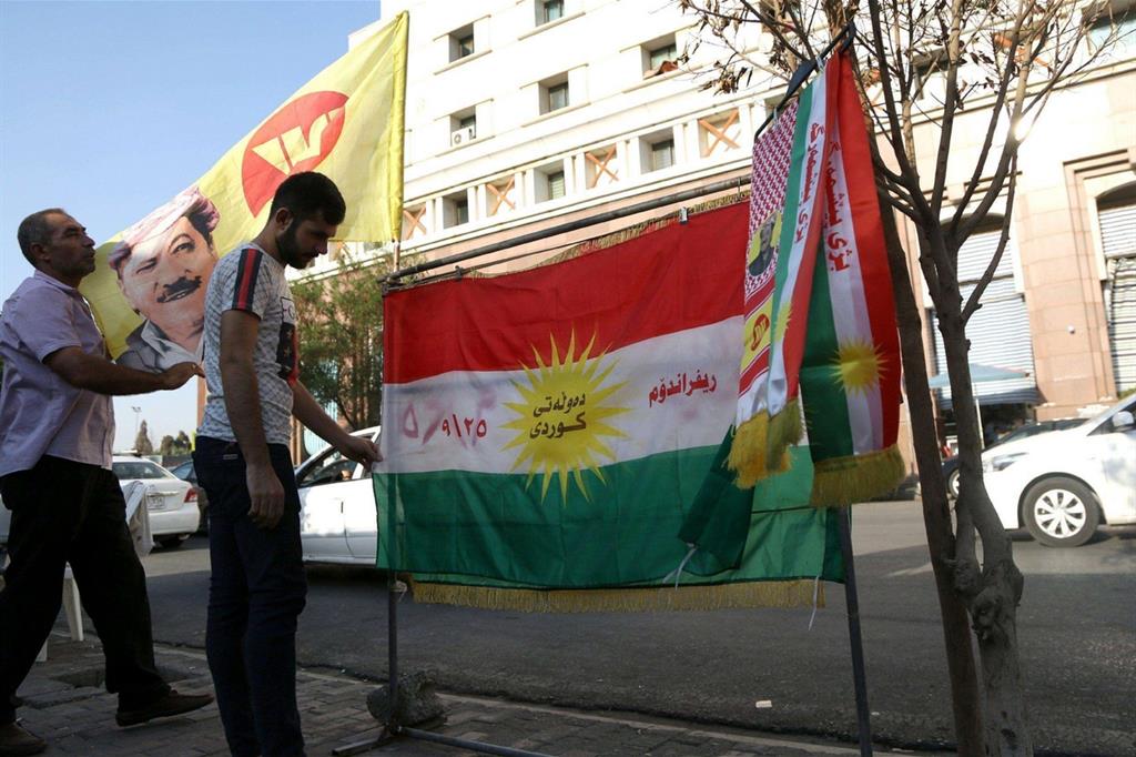 Due uomini con la bandiera del Kurdistan per le vie di Erbil (Ansa)