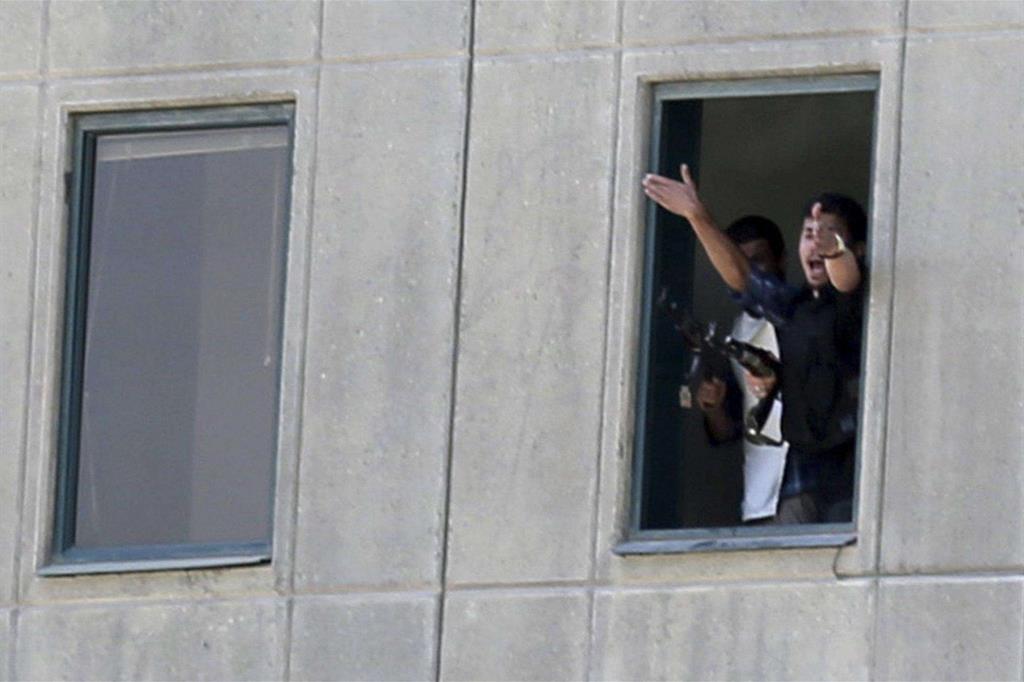 Un agente di sicurezza si sporge da una finestra del Parlamento di Teheran durante lo scontro con i terroristi (Ansa)