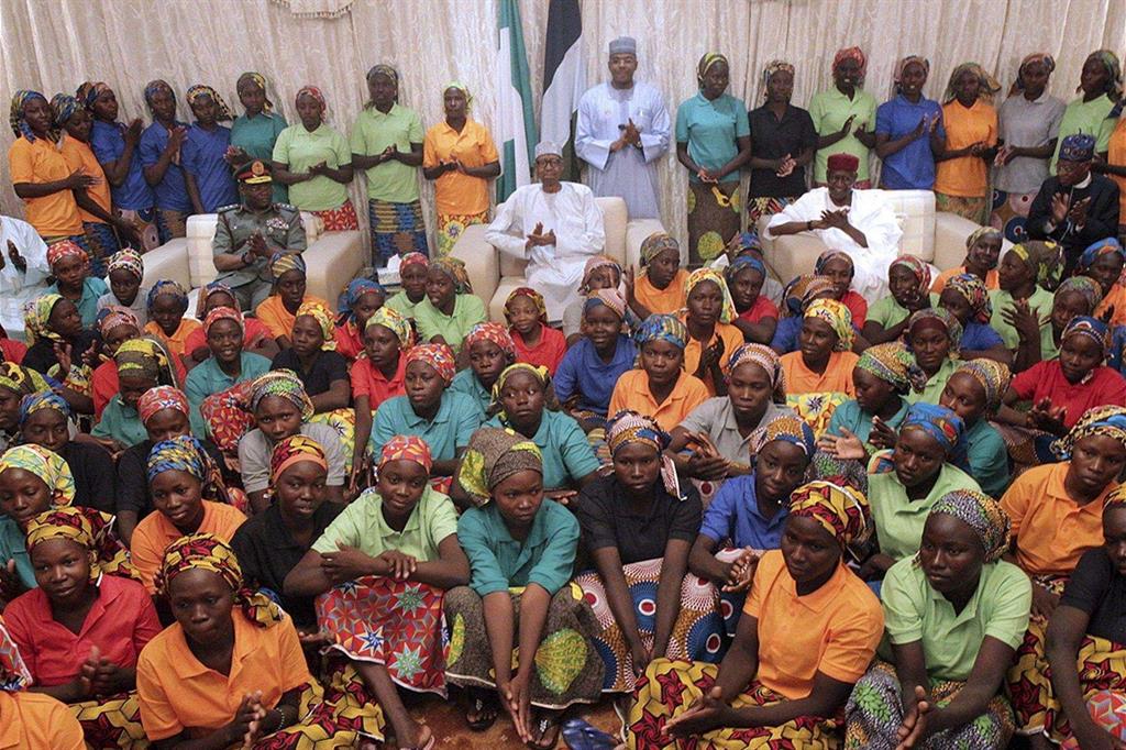 Le ragazze liberate con il presidente Buhari (al centro, con il copricapo bianco) (Ansa)