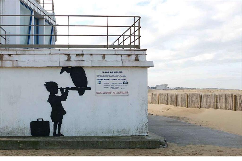 A dicembre 2015 di fronte a una spiaggia di Calais, Banksy aveva realizzato uno stencil che raffigurava un bambino con una valigia, che guardava in direzione dell'Inghilterra con un un cannocchiale sul quale si è appollaiato un avvoltoio. (Foto dal sito www.banksy.co.uk) - 