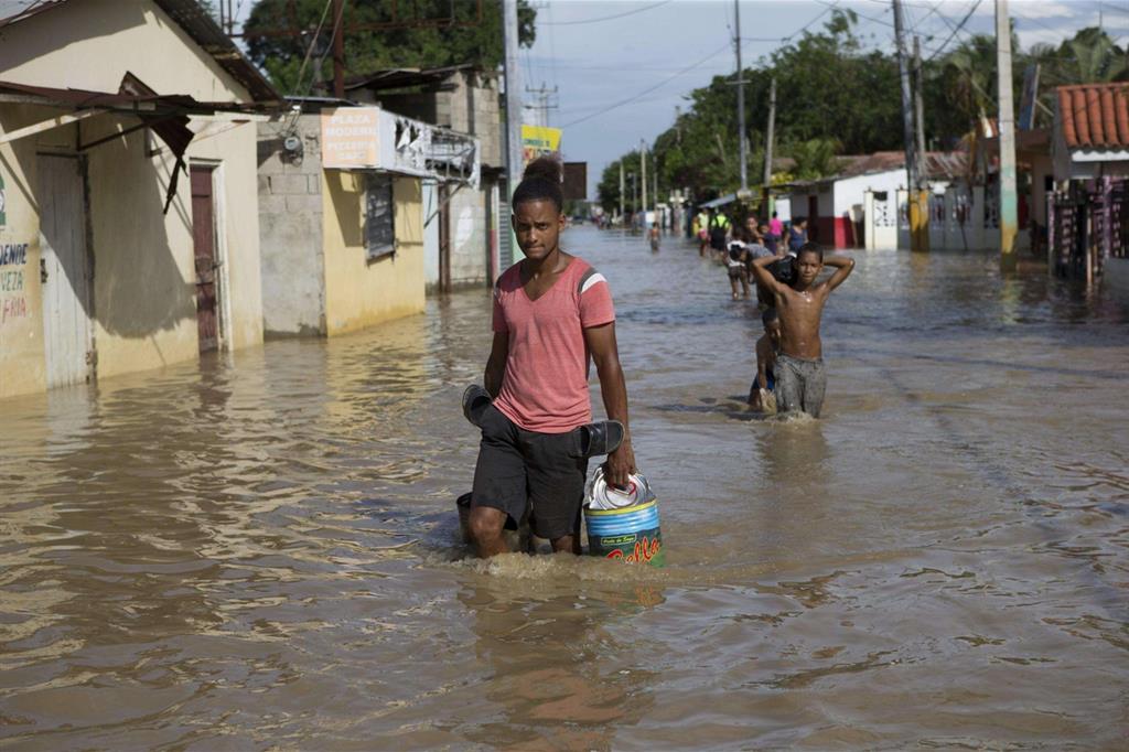 La gente cammina in una strada sommersa dall'acqua dopo l'uragano Maria ad Arenoso, nella Repubblica Dominicana . (Ansa) - 