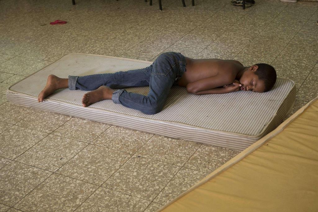 Un ragazzo dome in un rifugio per gli sfollati di Arenoso, nella Repubblica Dominicana (Ansa) - 