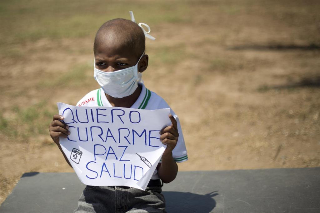 Un bimbo chiede aiuti per potersi curare durante una manifestazione a Caracas (Ansa/Ap)