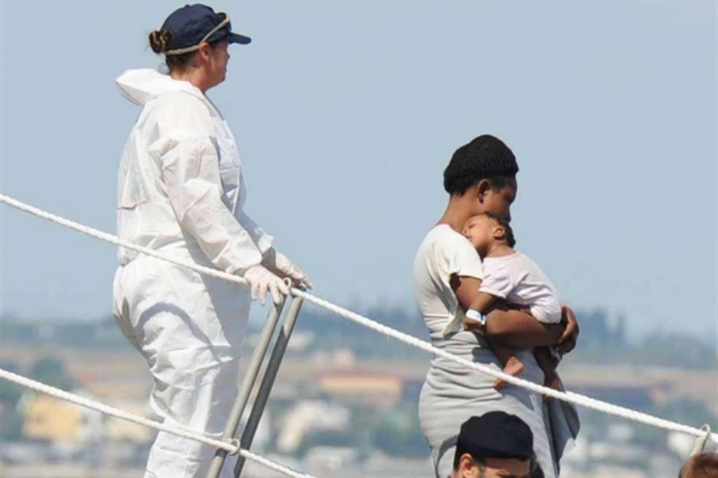 Una giovane immigrata sbarca con suo bambino (Fotogramma)