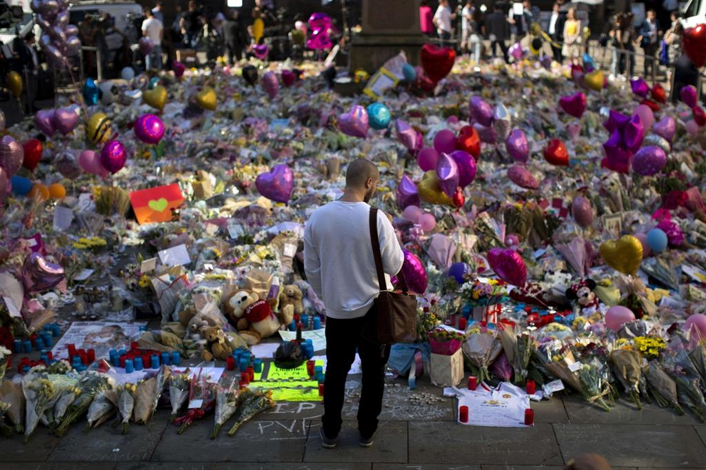Un uomo rende il suo omaggio floreale alle vittien dell'attentato alla St. Ann square di Manchester (Ansa)