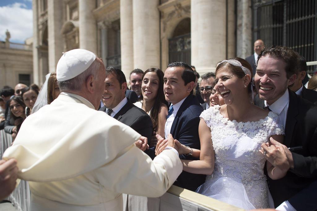 Il Papa saluta una coppia di sposi durante un'udienza generale in piazza San Pietro (Ansa)