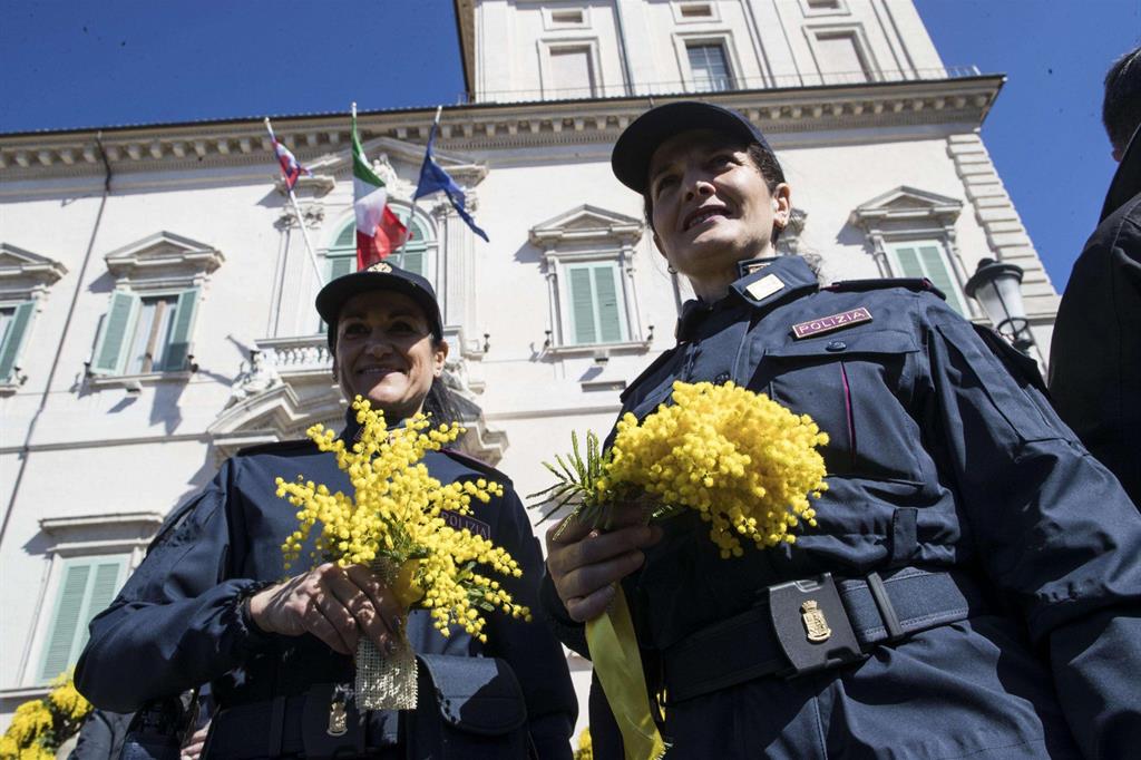Due poliziotte con in mano la mimosa davanti al Quirinale (Ansa)