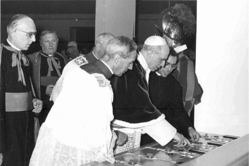 Pio XII alla Radio Vaticana. Padre Stefanizzi, alla sinistra del Papa, spiega il funzionamento della consolle