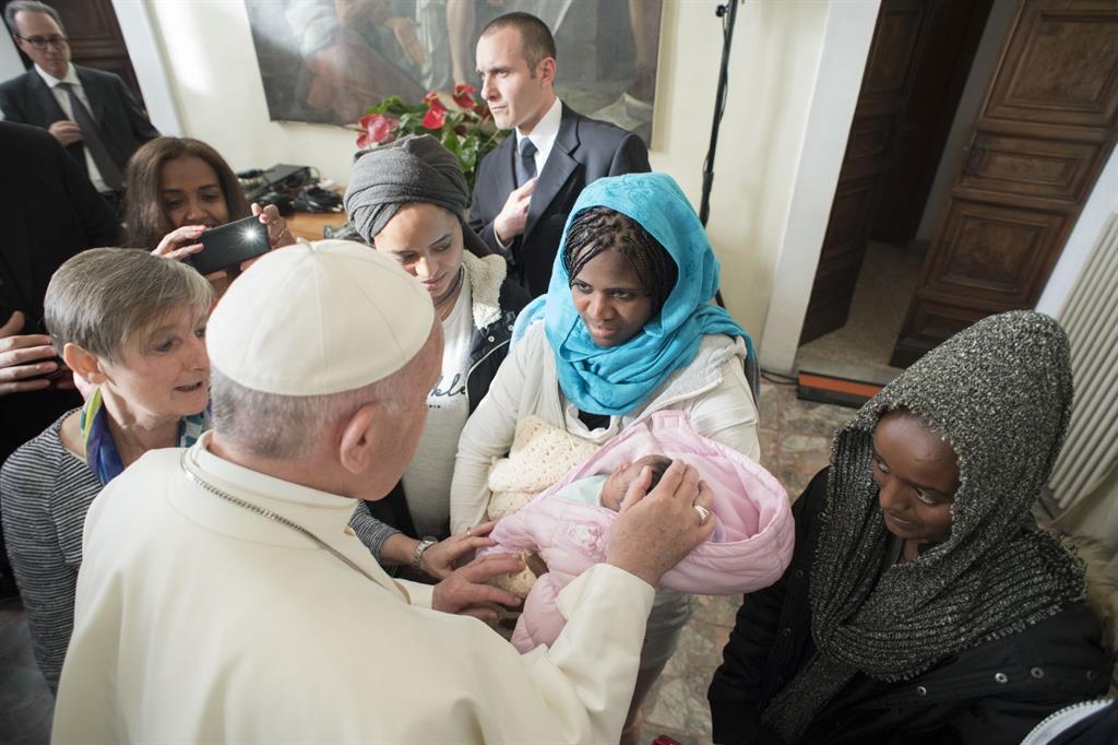 Papa Francesco accarezza un neonato durante un incontro con alcune donne migranti