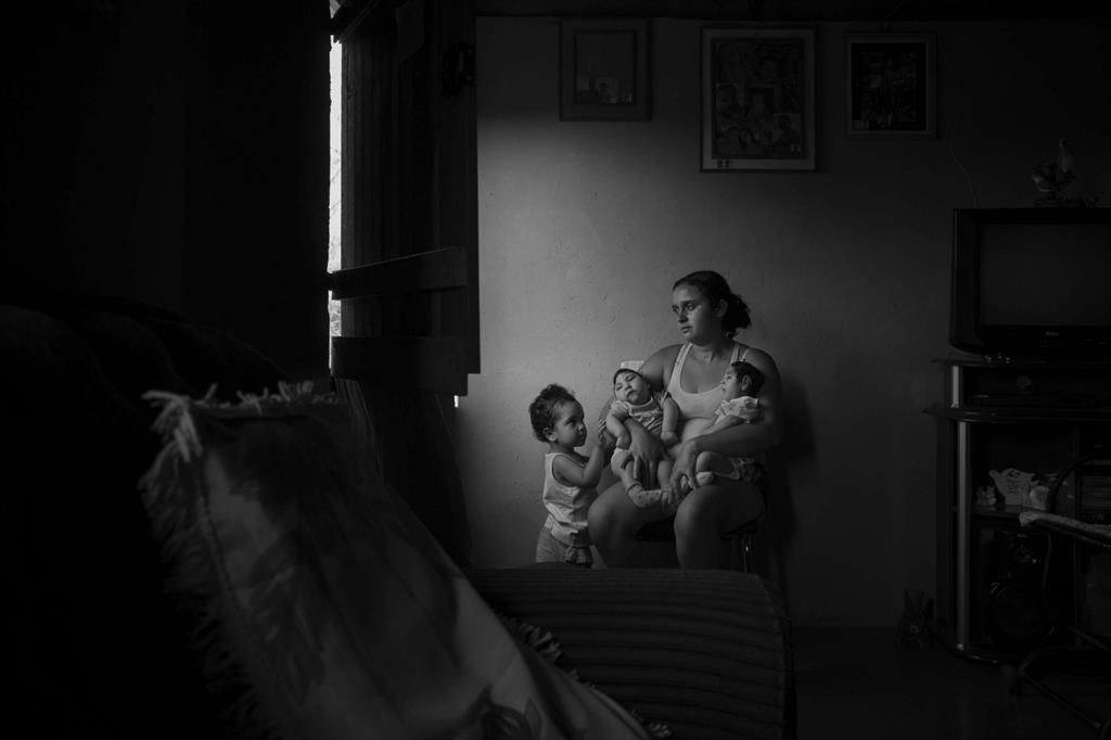 La piccola Marcela, 2 anni, osserva le sorelle in braccio alla madre, nella casa di famiglia nella zona rurale di Areia. Le gemelle Heloisa (a sinistra) e Heloa (a destra), di 7 mesi, sono nate con microcefalia causata dal virus Zika. Foto Lalo de Almeida, Folha de Sao Paulo. - 