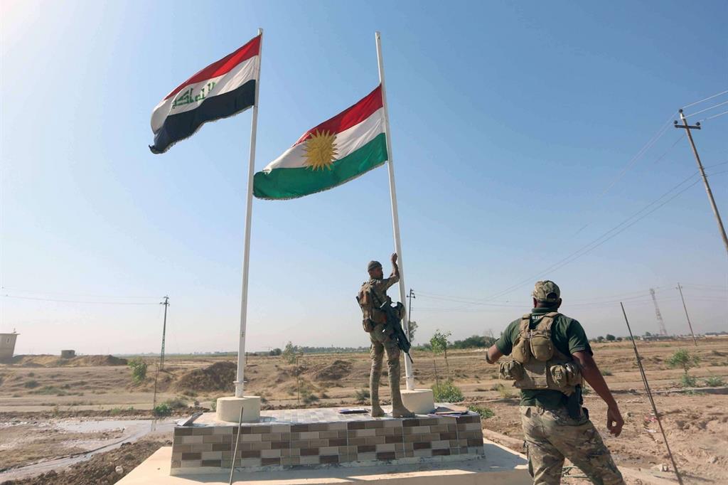 Un soldato irachneio ammaina la bandiera del Kurkdista a Kirkuk (Reuters)