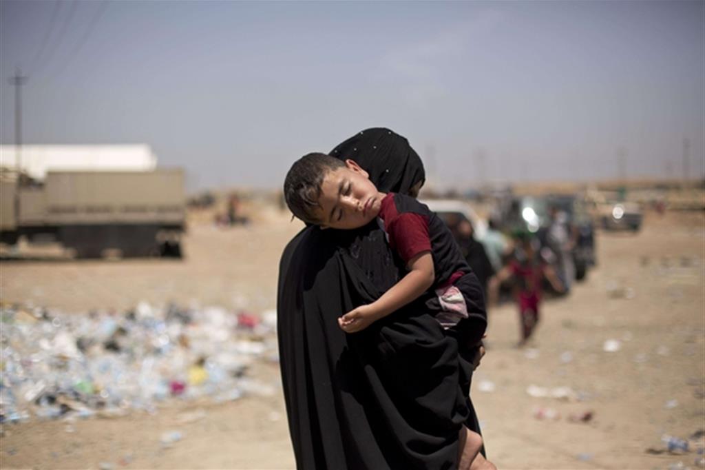 Una donna irachena con il figlio lascia con altri sfollati la periferia orientale di Mosul (Mosul)