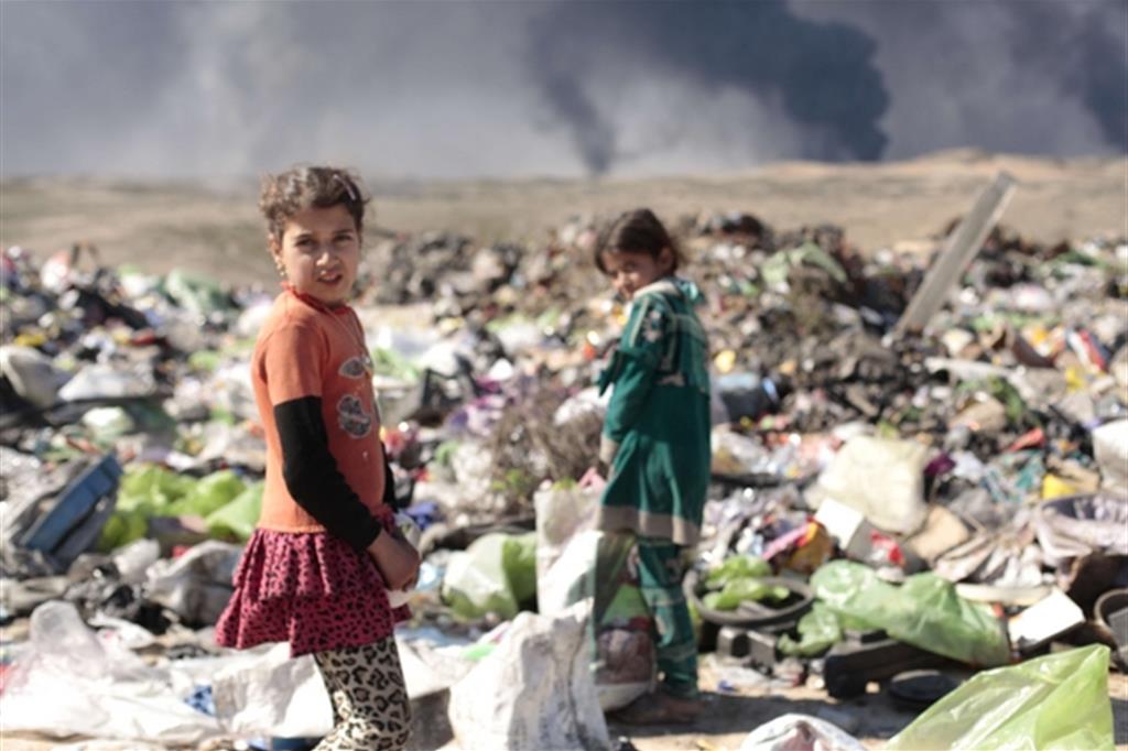 Bambini raccolgono dalla spazzatura avanzi di lamiere e materiali da riciclo fuori Qayyara (Battaglia)
