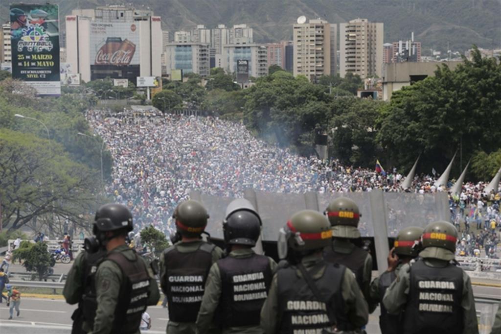La polizia osserva da lontano l'imponente manifestazione nel centro della capitale Caracas (Ansa/Ap)