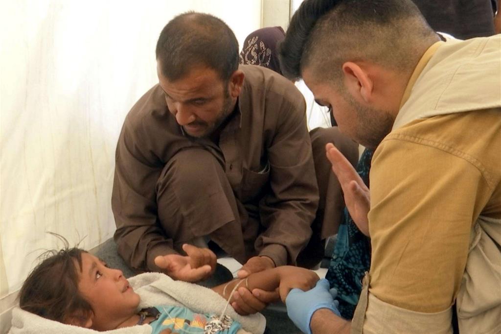 I medici si prendono cura di una bambina nel campo profughi (Ansa)