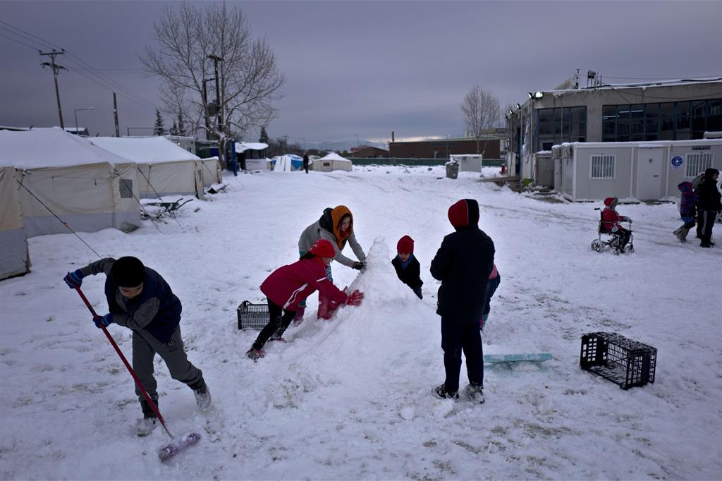Dei bambini afghani nel campo greco di Oinofyta a 58 chilometri da Atene, in Grecia, sono intenti a costruire un pupazzo di neve. Foto: Muhammed Muheisen/Ansa - 
