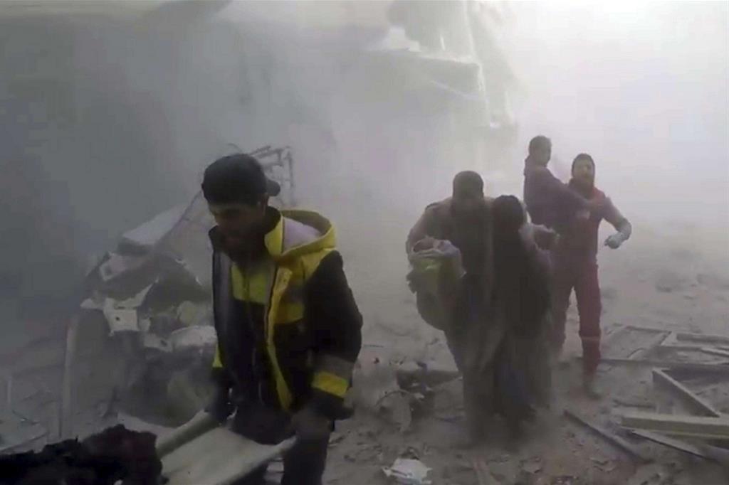 Il Gruppo di difesa civile siriano (gli "Elmetti bianchi") aiuta i residenti a mettersi in salvo durante i bombardamenti su Ghouta, il martoriato sobborgo di Damasco (Ansa)