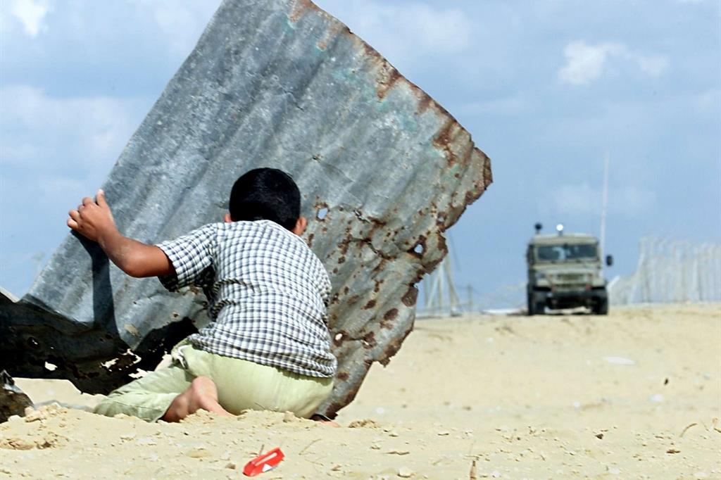 Un bambino palestinese si nasconde durante gli scontri a Khan Yunes nella Striscia di Gaza (Ansa)