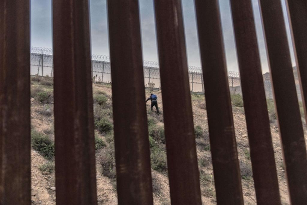 Un migrante honduregno mentre prova a superare il confine con gli Stati Uniti a Tijuana, in Messico (Foto Ansa)