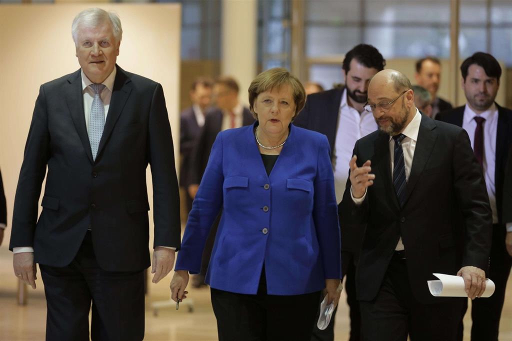 Angela Merkel tra Horst Seehofer (a sinistra) e Martin Schulz al termine della maratona negoziale (Ansa)