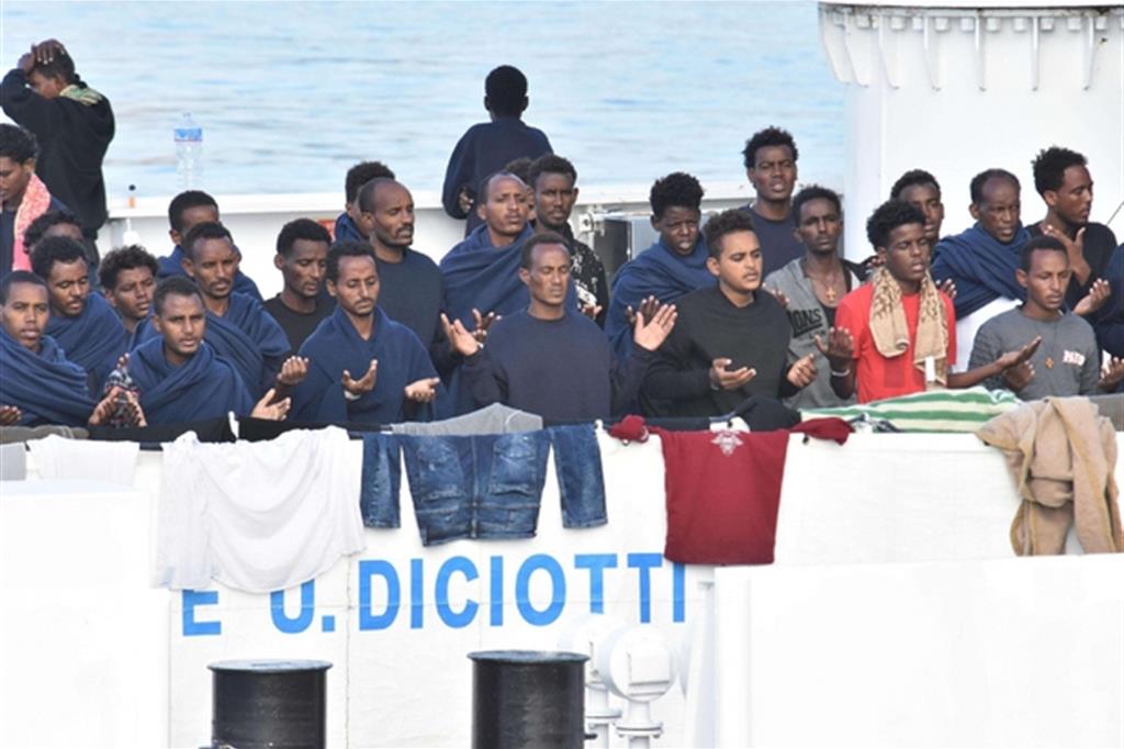 Le persone sulla nave Diciotti mentre pregano di essere sbarcate a terra (Ansa)