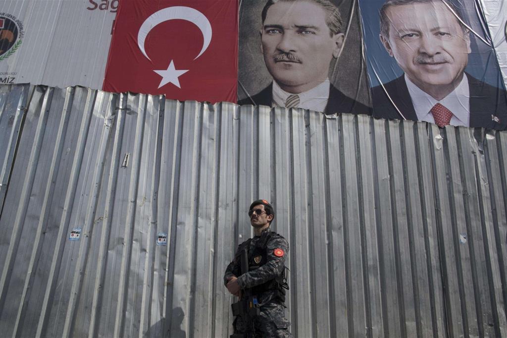Un soldato delle Forze speciali turche sotto manifesti raffiguranti il padre della Turchia moderna, Mustafa Kemal Ataturk, e l'attuale presidente Recep Tayyip Erdogan a Istanbul (Ansa)
