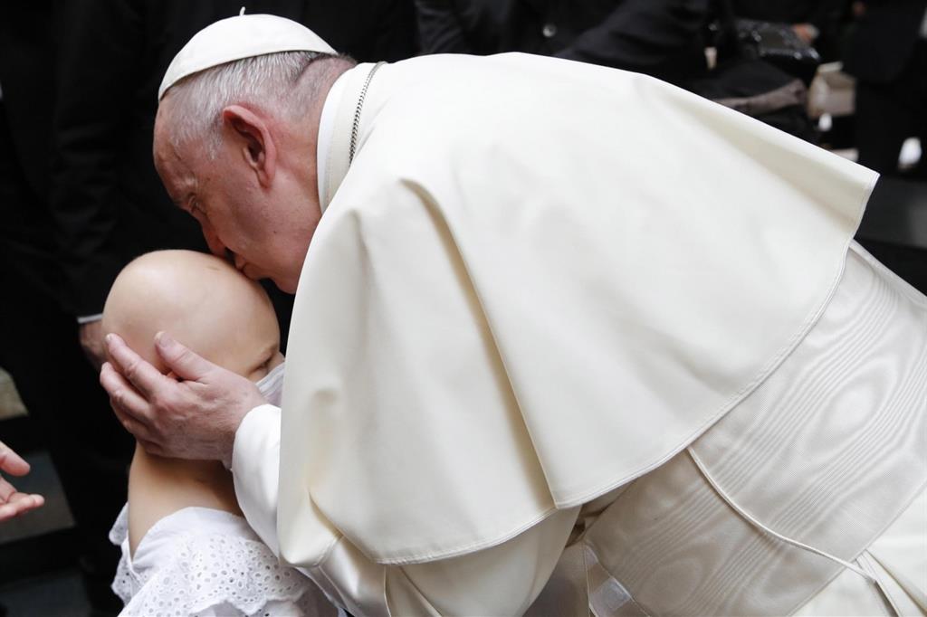 Il Papa bacia una bambina ammalata, in un'immagine di repertorio (Ansa)