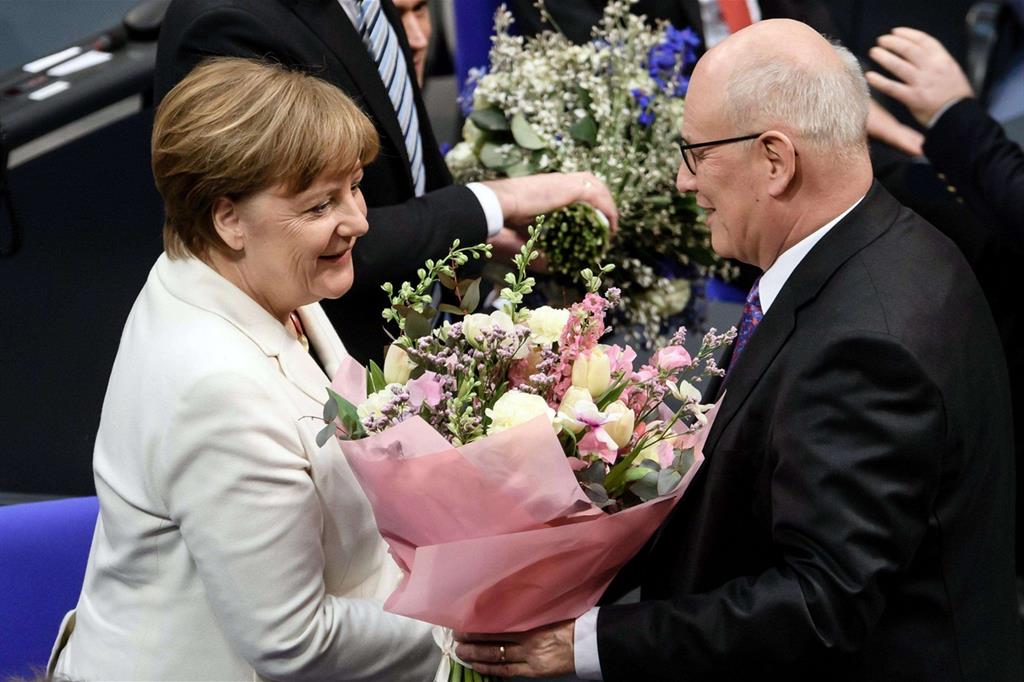 Dopo il voto, Angela Merkel riceve un mazzo di fiori dal leader del gruppo parlamentare Cdu/Csu Volker Kauder (Ansa)