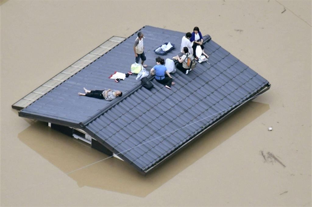 Una famiglia rifugiata sul tetto di casa in attesa dei mezzi di soccorso a Kurashiki, Okayama (Ansa)