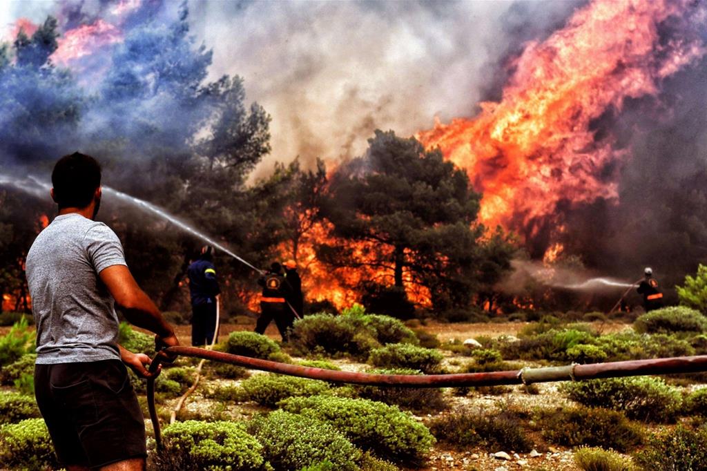 Vigili del fuoco e volontari cercano di estinguere un incendio a Verori, vicino a Loutraki, nel Peloponneso (Ansa)