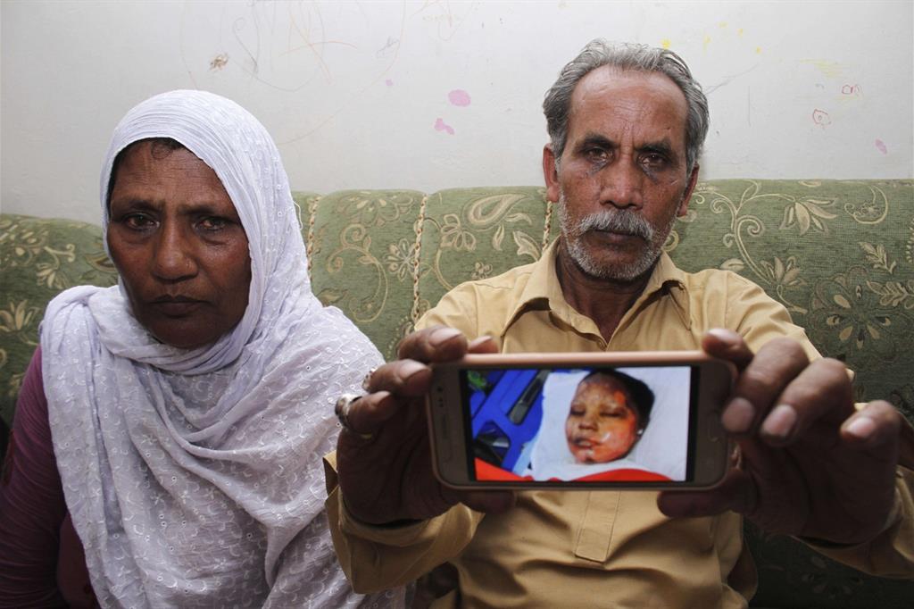 I genitori di Asima mostrano una foto della figlia dopo l'aggressione (Ansa)