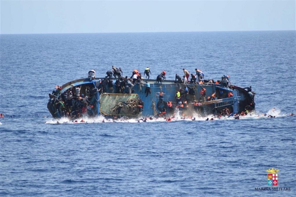 L'immagine di una barca carica di migranti che si rovescia al largo della Libia, ripresa dalla Marina militare italiana nel 2016 (Ansa)
