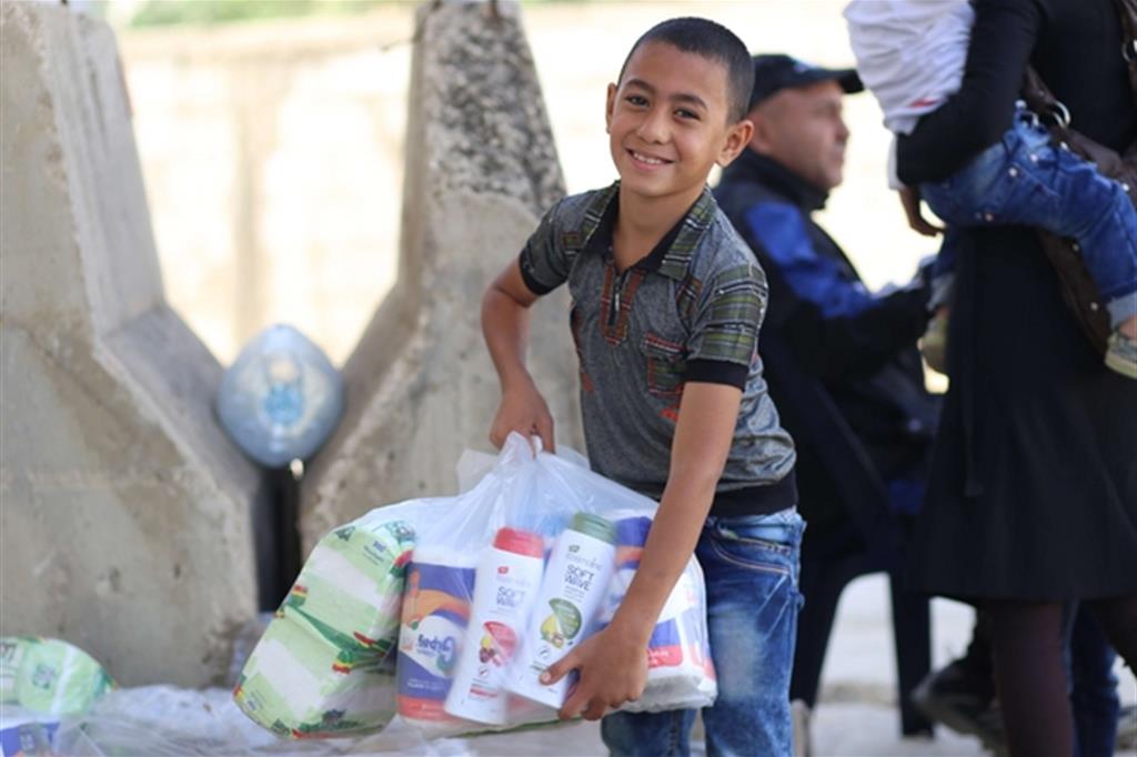 Bimbo siriano con un sacchetto di aiuti per la sua famiglia: Caritas e Ong Focsiv forniscono ogni giorno generi alimentari