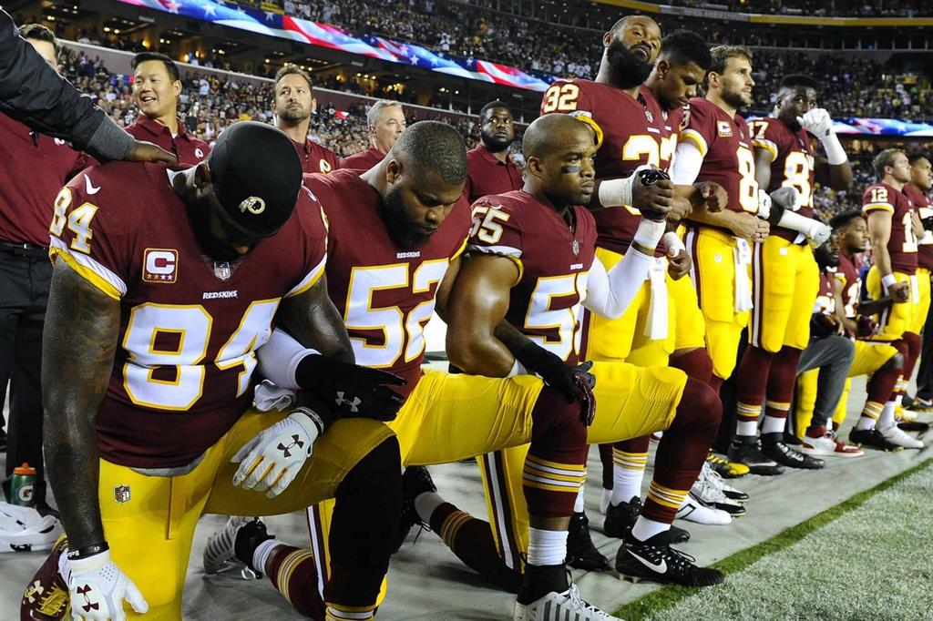 Giocatori dei Washington Redskins ascoltano l'inno nazionale in ginocchio: la protesta è nata dal gesto di Colin Kaepernick dei San Francisco 49ers ed è stata imitata da decine di giocatori della Nfl