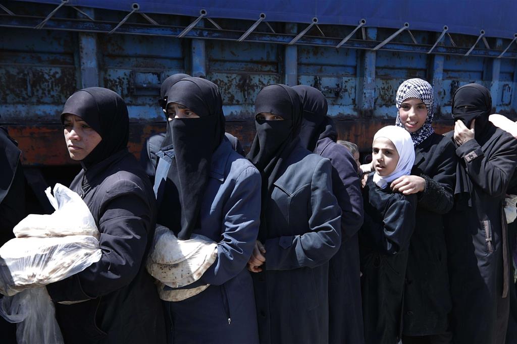 Donne in fila per ricevere aiuti alimentari. Le autorità siriane, entrate a Douma due giorni fa, hanno distribuito pane, verdura e pasta - 