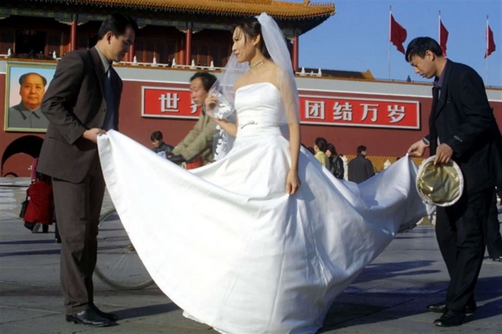 Le fotografie di rito sulla piazza Tienanmen per una sposa pechinese (Ap)