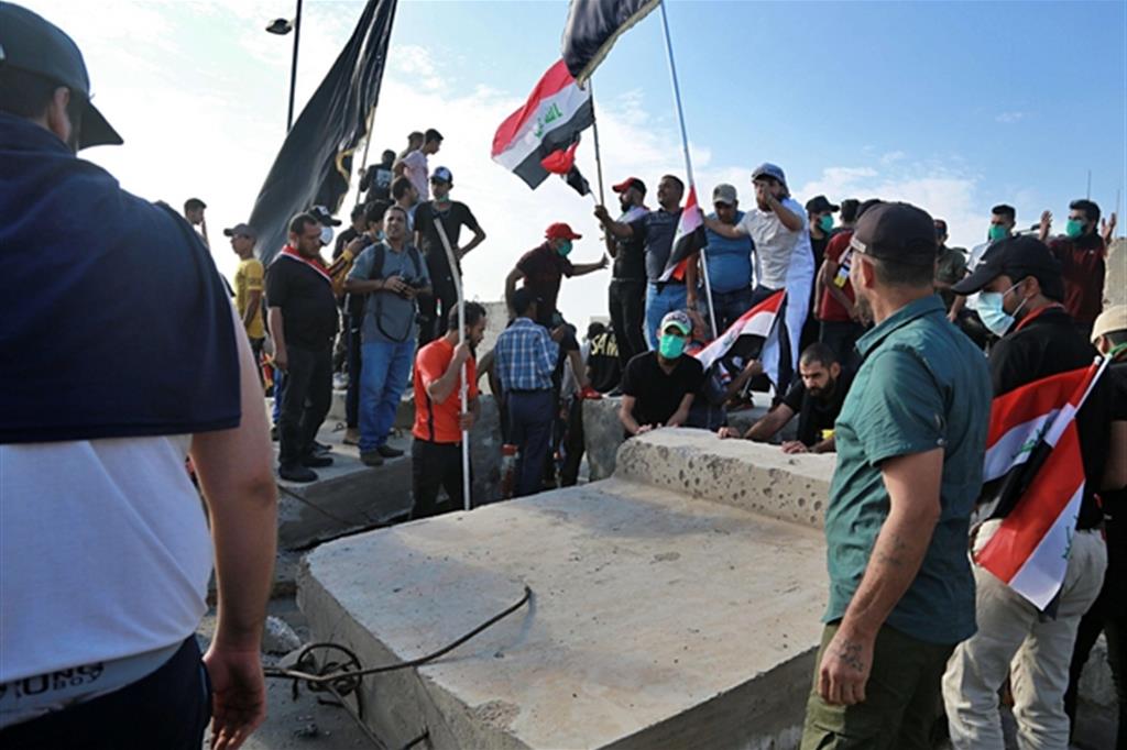 Manifestanti antigovernativi abbattono un muro su un ponte nel centro di Bagdad (Ansa)