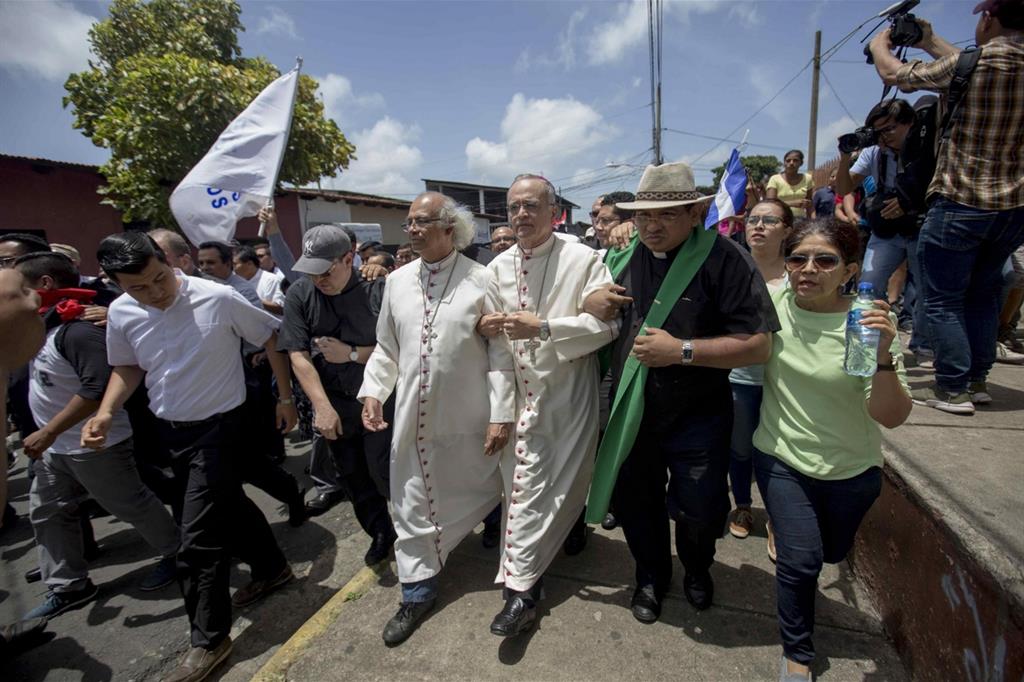 Il cardinale Leopoldo Brenes (al centro), arcivescovo di Managua, e il vescovo Silvio Baez (a destra) in marcia davanti alla basilica di San Sebastian, a Diriamba, per liberare un gruppo di paramedici e missionari francescani assediati nella chiesa da sostenitori del governo il 9 luglio scorso (Ansa)