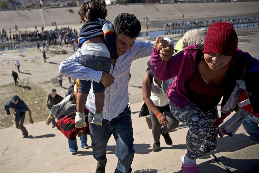 Migranti nei pressi di un punto di confine tra Messico e Stati Uniti vicino a Tijuana (Ansa)