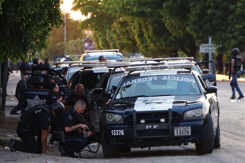 Gli agenti si proteggono dietro le auto durante la sparatoria a Culiacan (Ansa)