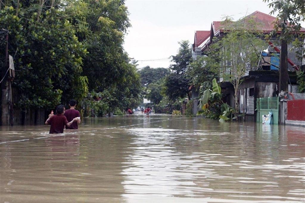 Alcuni residenti di Bulan cercano di uscire dalla città attraversando le strade inondate (Ansa)