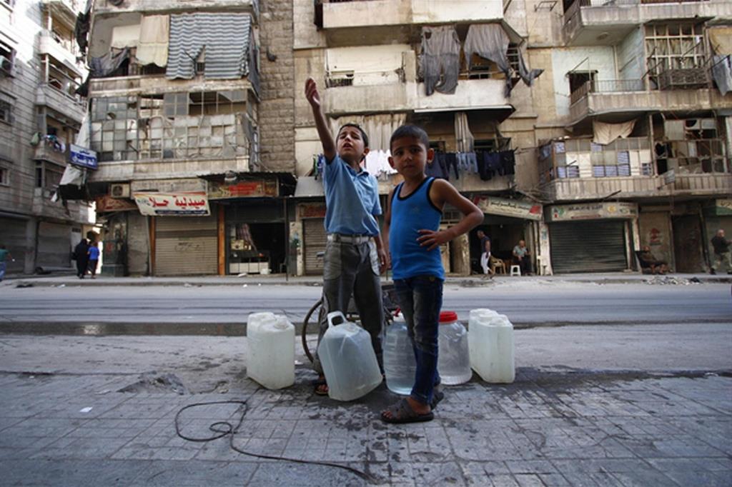 Aleppo: bambini impegnati nell'approvvigionamento di acqua nella Siria martoriata dalla guerra (Ansa)