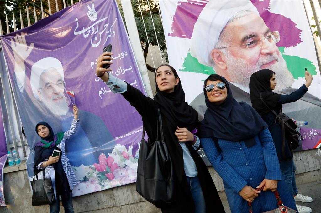 Selfie a Teheran davanti a manifesti di Rouhani (Ansa)