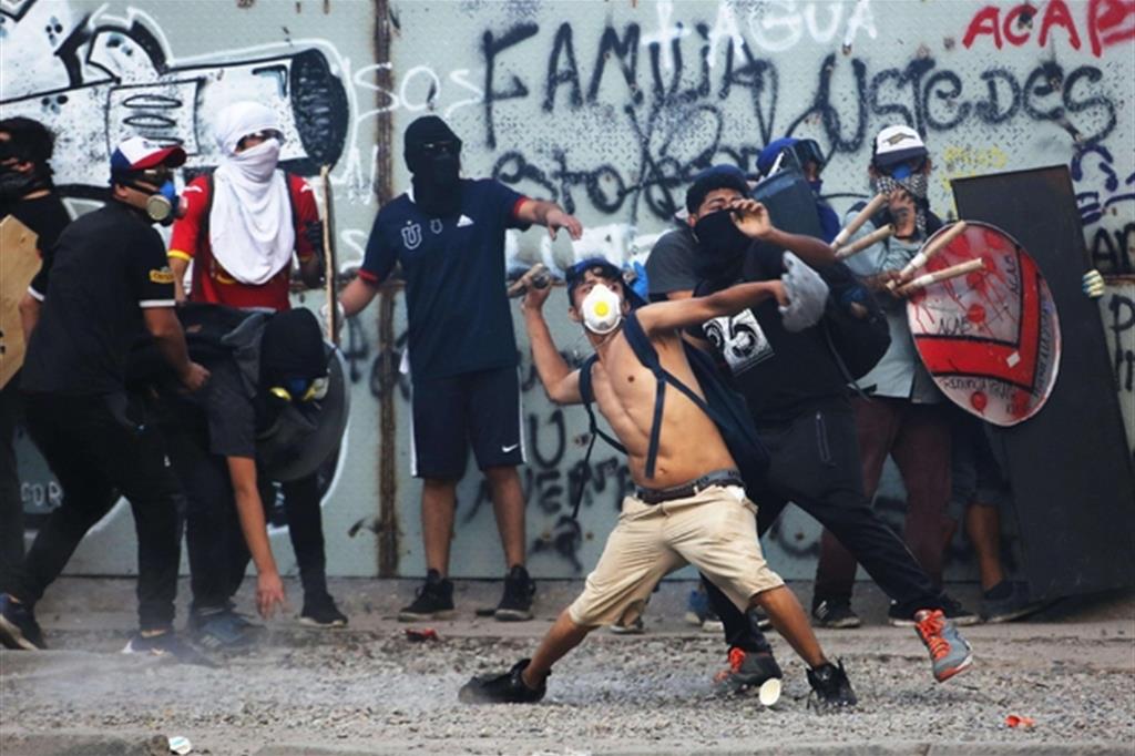 Lancio di pietre contro la polizia a Santiago del Cile (Ansa)