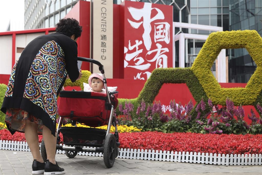Una donna fotografa una bambina davanti a un cartello "Made in China" nel distretto commerciale di Pechino (Ansa-Ap)