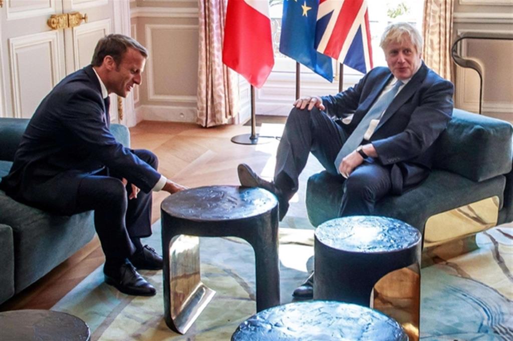 L'imbarazzo di Emmanuel Macron al piede del premier britannico Boris Johnson appoggiato sul tavolino durante l'incontro all'Eliseo (Ansa)