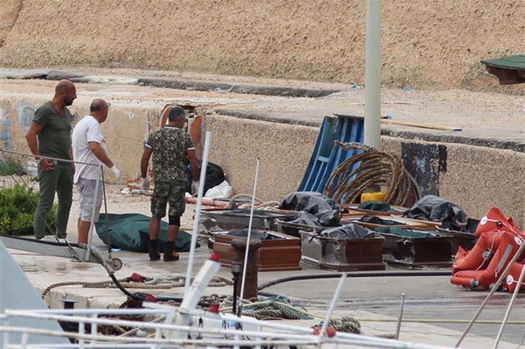 Sul molo di Lampedusa si allineano le bare per le vittime del naufragio (Ansa)