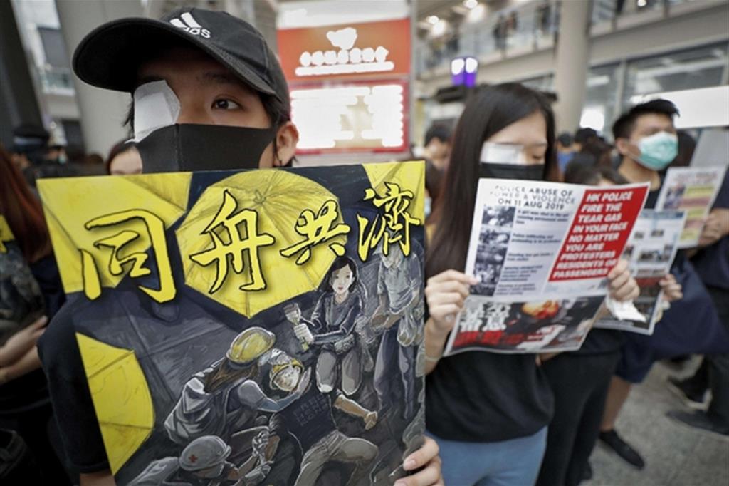 L'aeroporto di Hong Kong occupato dai manifestanti. Un occhio coperto in segno di  solidarietà con un manifestante ferito (Ansa)