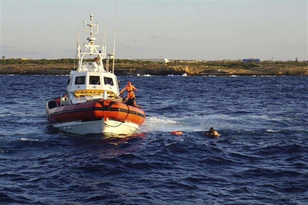 Motovedette in soccorso dei migranti che si sono gettati in mare (Ansa)