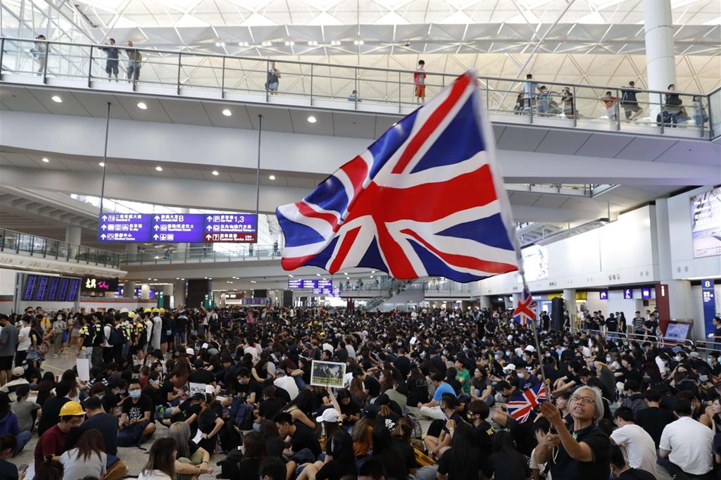 Una manifestante sventola la bandiera britannica durante le proteste all'aeroporto di Hong Kong (Ansa)